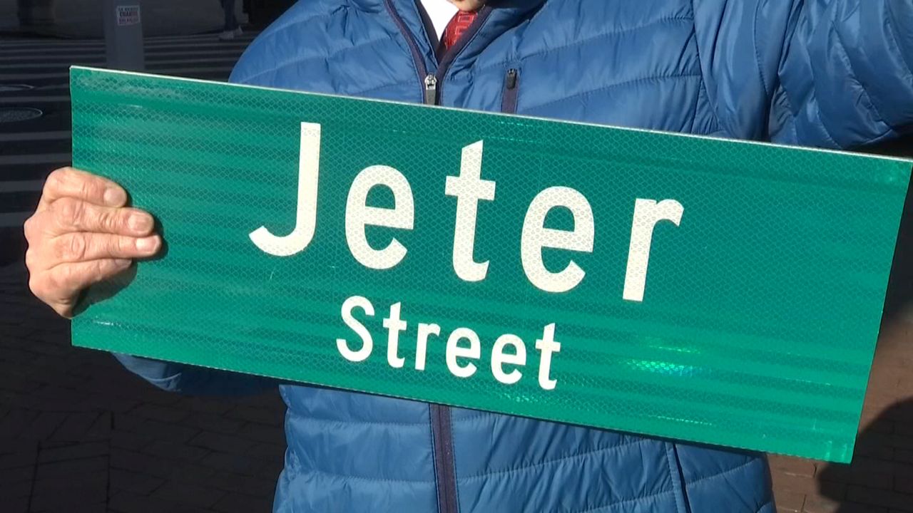 A person holds a up a green sign with white text for "Jeter Street."