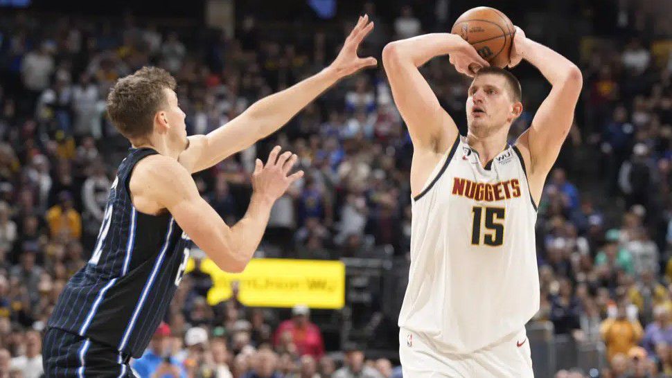 Denver Nuggets center Nikola Jokic, right, shoots a winning 3-point basket over Orlando Magic forward Franz Wagner late in the second half of an NBA basketball game Sunday, Jan. 15, 2023, in Denver. (AP Photo/David Zalubowski)