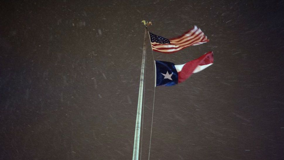The United States flag and Texas state flag wave as snow falls in downtown Tyler, Texas early on Tuesday morning Jan. 16, 2018 as a winter storm moves into the area. (Sarah A. Miller/Tyler Morning Telegraph)