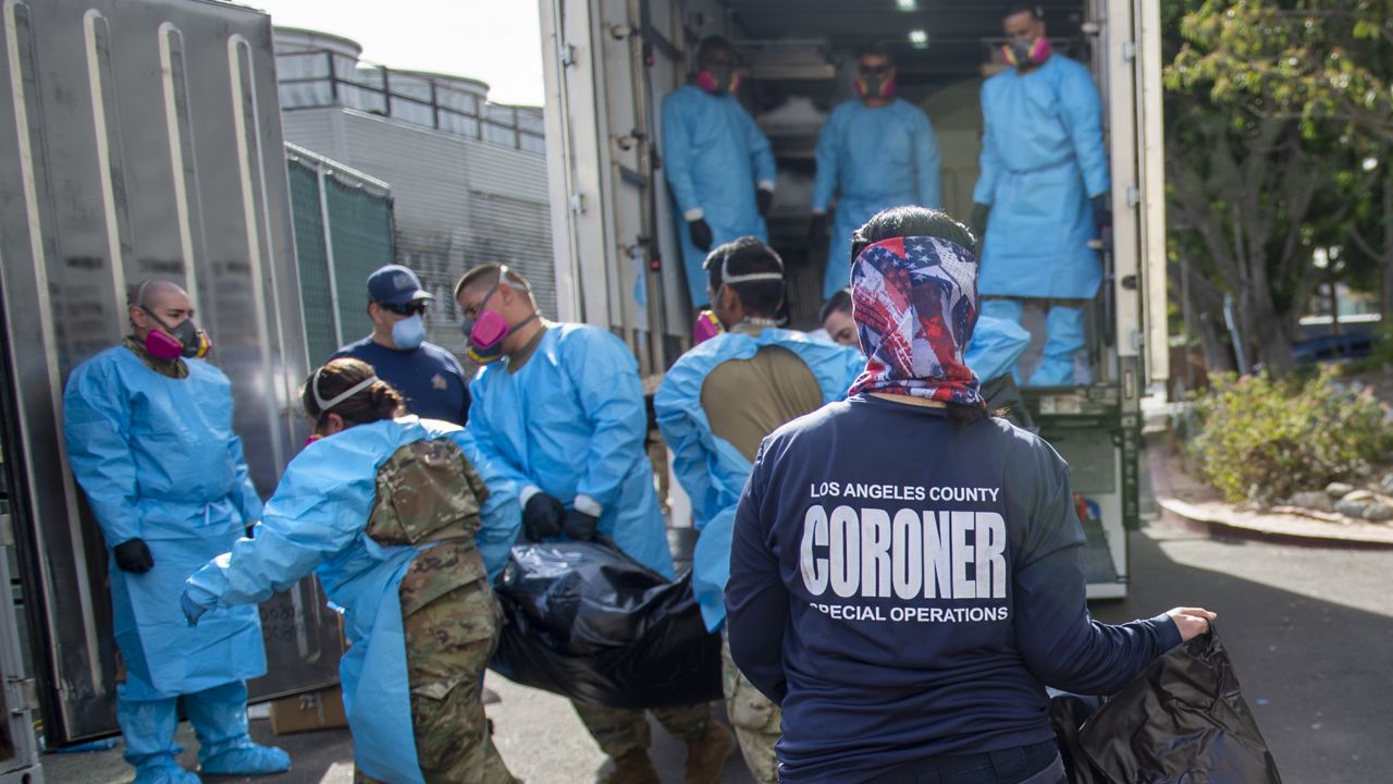 Coroner Elizabeth "Liz" Napoles, right, works alongside with National Guardsmen who are helping to process the COVID-19 deaths to be placed into temporary storage at LA County Medical Examiner-Coroner Office in Los Angeles. (LA County Dept. of Medical Examiner-Coroner via AP)