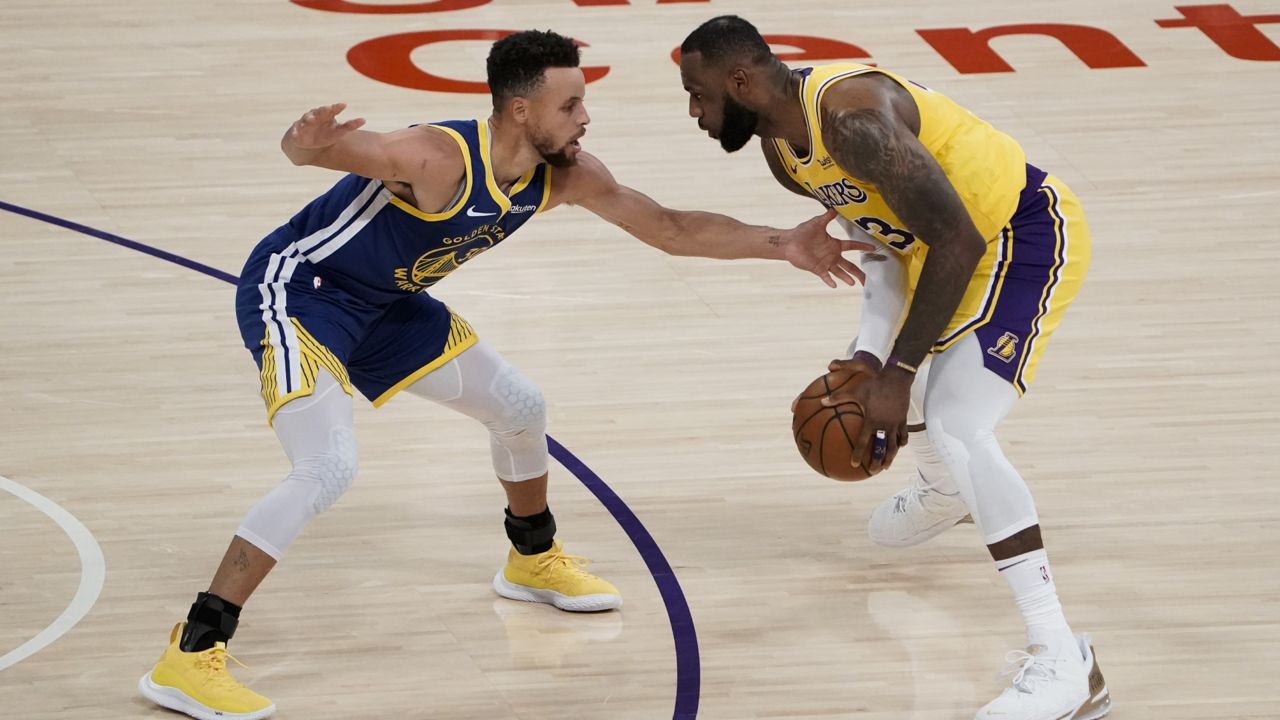 Golden State Warriors' Stephen Curry, left, pressures Los Angeles Lakers' LeBron James during the first half of an NBA basketball game, Monday, Jan. 18, 2021, in Los Angeles. (AP Photo/Jae C. Hong)