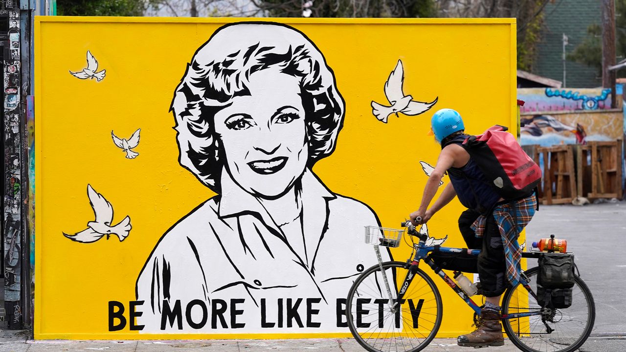 A cyclist rides by a new mural of the late actress Betty White by artist Corie Mattie, Tuesday, Jan. 13, 2022, in Los Angeles. (AP Photo/Chris Pizzello)