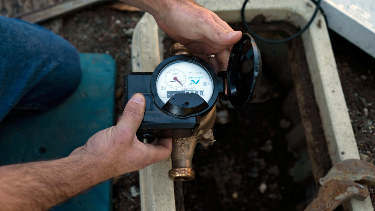 Cason Gilmer, a senior field customer service representative from the Las Virgenes Municipal Water District, installs an advanced water metering system in Agora Hills , Calif., Wednesday, Jan. 5, 2022. (AP Photo/Jae C. Hong)