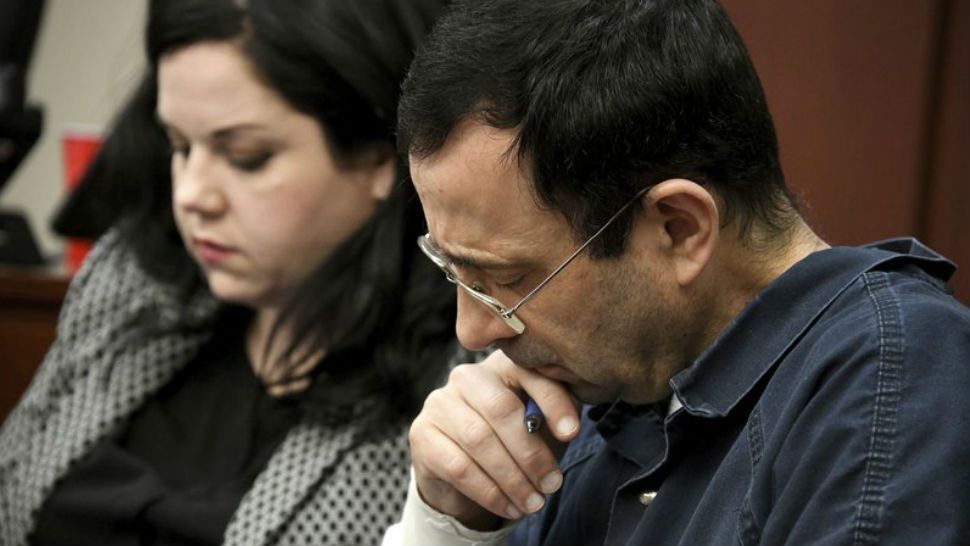 A victim makes her “impact statement” to Larry Nassar during a sentencing hearing as he puts his head down in front of Judge Rosemarie Aquilina in district court on Tuesday, Jan. 16, 2018, in Lansing, Mich. Nassar has pleaded guilty to molesting females with his hands at his Michigan State University office, his home and a Lansing-area gymnastics club, often while their parents were in the room. (Dale G. Young/Detroit News via AP)