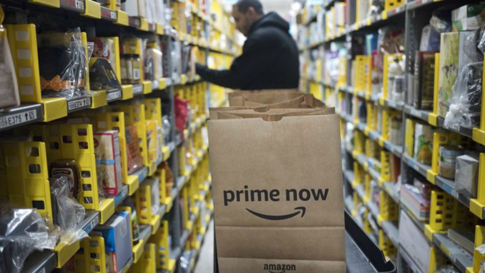 FILE - In this Wednesday, Dec. 20, 2017, file photo, a clerk reaches to a shelf to pick an item for a customer order at the Amazon Prime warehouse, in New York. (AP Photo/Mark Lennihan, File)