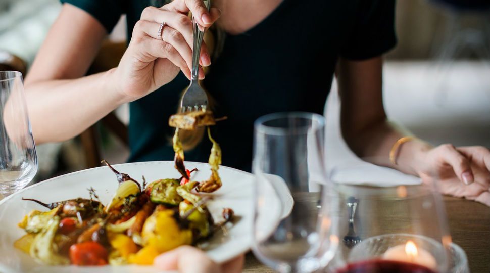 People sharing plate of food in restaurant (Stock Image)