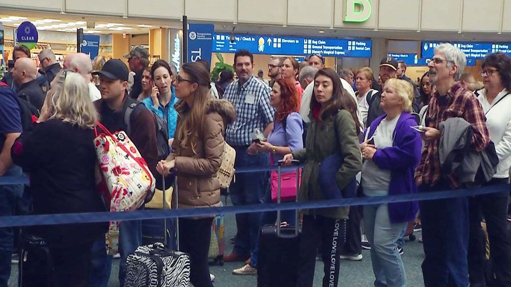 Passengers wait at security at Orlando International Airport, with dozens of flights canceled or delayed. (Spectrum News)