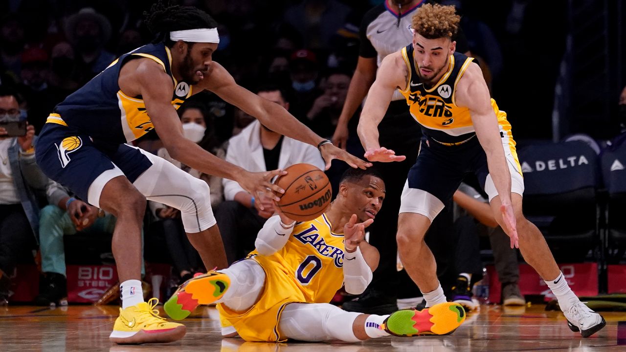 Los Angeles Lakers guard Russell Westbrook (0) passes from the floor against Indiana Pacers forward Isaiah Jackson, left, and guard Chris Duarte, right, during the second half of an NBA basketball game in Los Angeles, Wednesday, Jan. 19, 2022. (AP Photo/Ashley Landis)