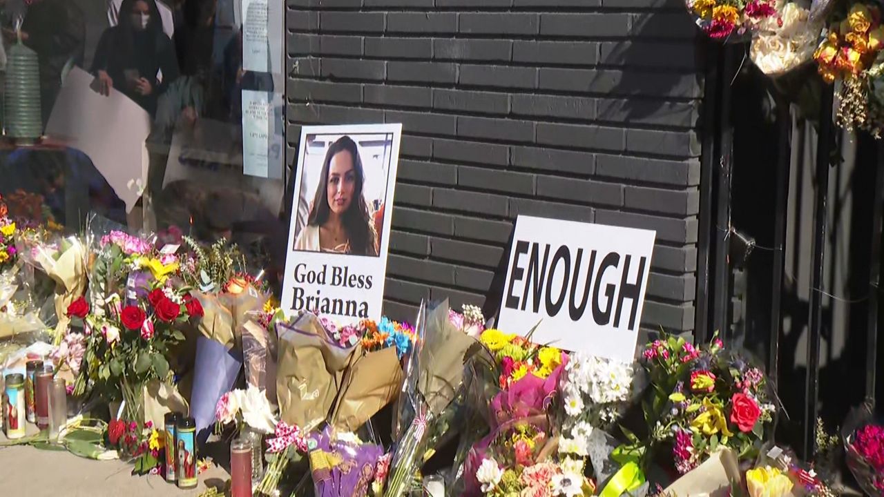 Flowers, candles and signs are left outside the Croft House in Hancock Park, where 24-year-old Brianna Kupfer was fatally stabbed last week. (Spectrum News)