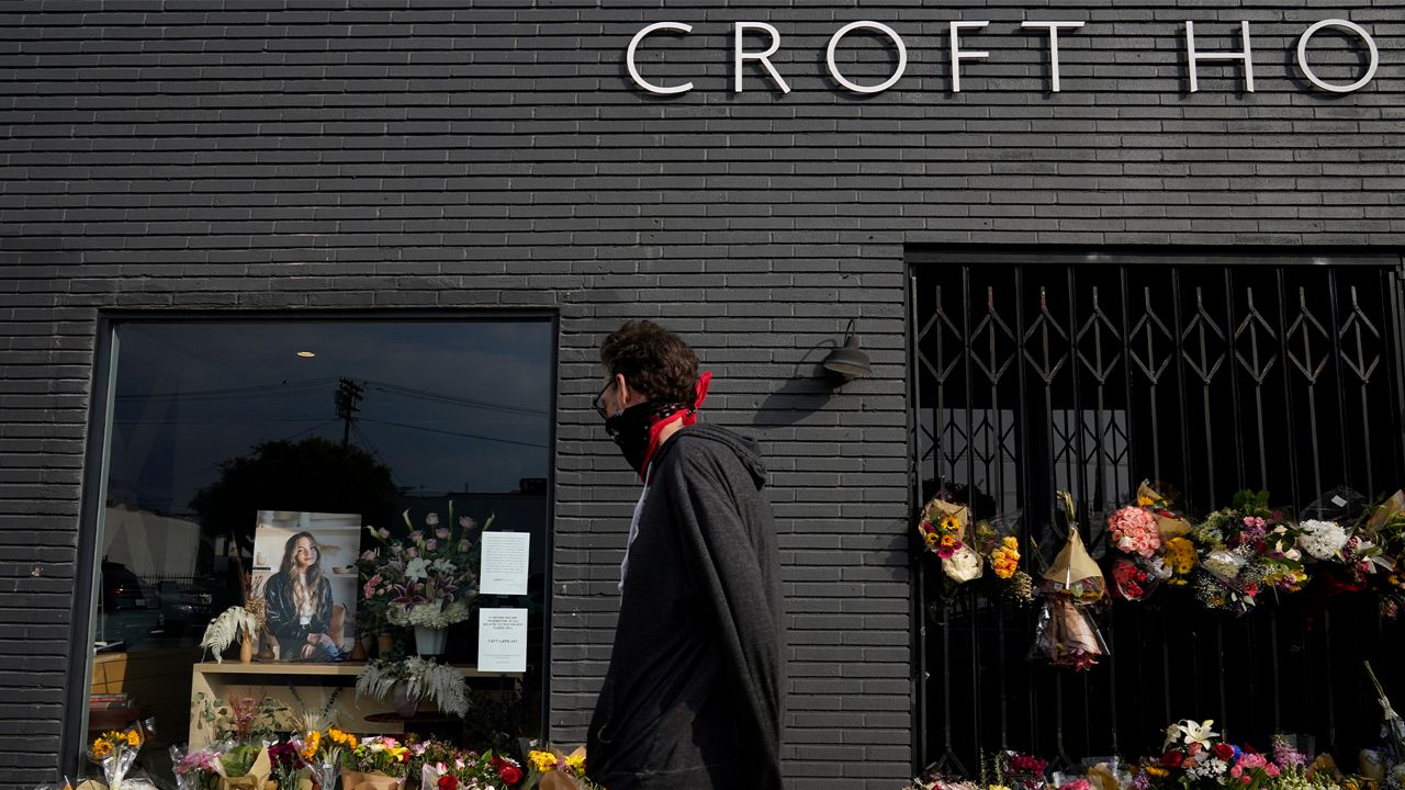 A man walks past flowers and candles that were placed outside Croft House store in honor of Brianna Kupfer on Tuesday, Jan. 18, 2022, in Los Angeles. (AP Photo/Ashley Landis)