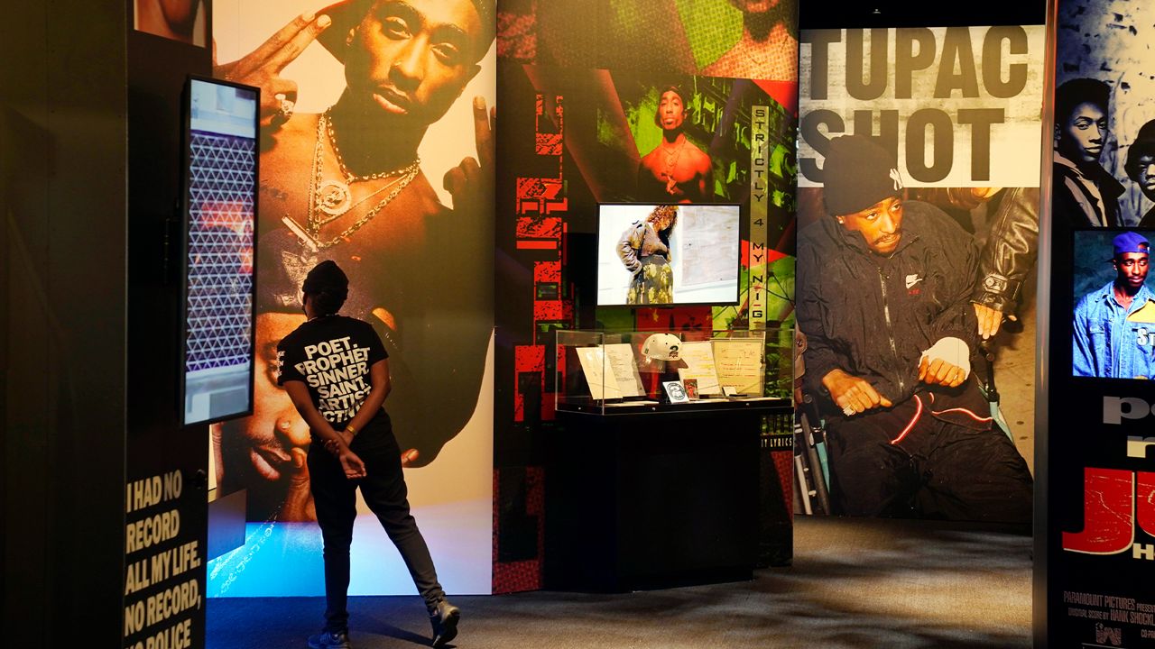 A visitor looks at a multimedia display on the life of the late hip hop artist Tupac Shakur during the press preview day for the "Tupac Shakur. Wake Me When I'm Free" exhibition, Thursday, Jan. 20, 2022, at The Canvas at L.A. Live in Los Angeles. (AP Photo/Chris Pizzello)