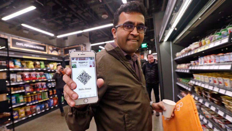 Amazon employee Krishna Iyer shows off an Amazon Go app as he shops in the store, Monday, Jan. 22, 2018, in Seattle. The store allows shoppers to scan their smartphone with the Amazon Go app at a turnstile, pick out the items they want and leave. The online retail giant can tell what people have purchased and automatically charges their Amazon account. (AP Photo/Elaine Thompson)
