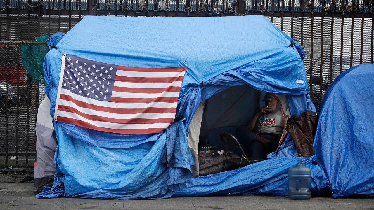 In this March 20, 2020, file photo, a man smokes inside a tent on skid row in Los Angeles. (AP Photo/Marcio Jose Sanchez)