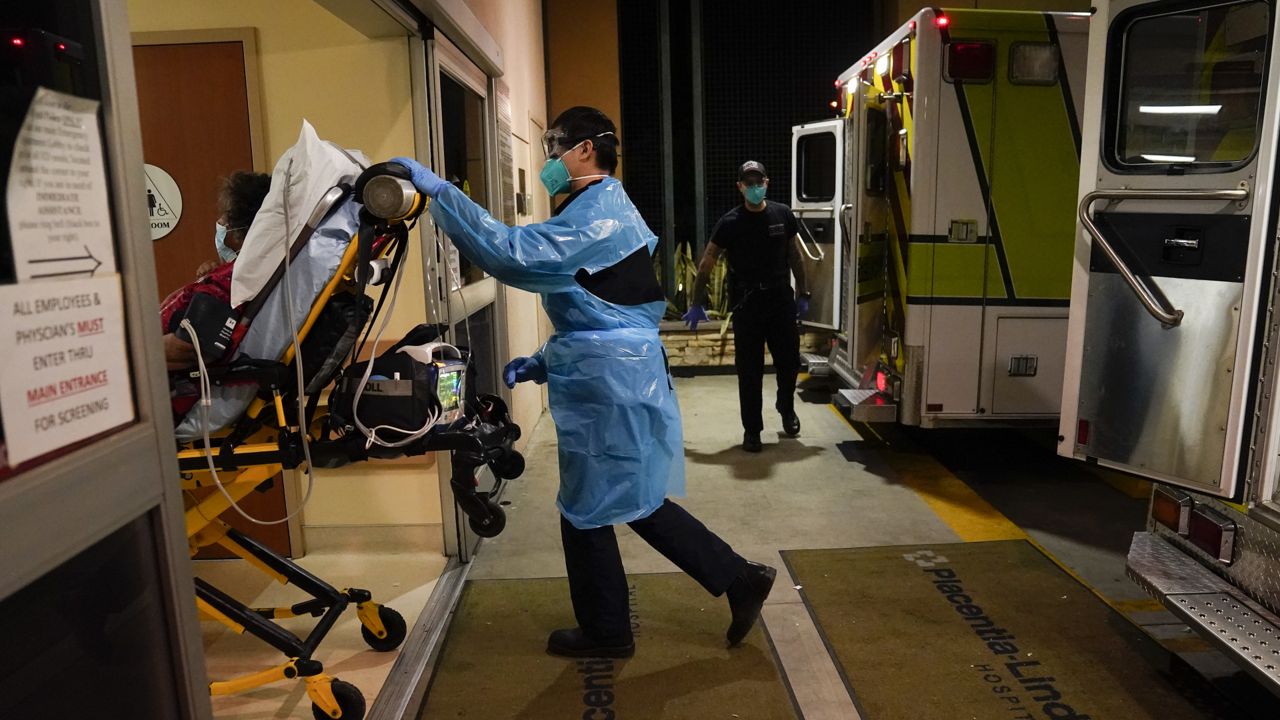 Emergency medical technician Thomas Hoang, 29, of Emergency Ambulance Service, pushes a gurney into an emergency room to drop off a COVID-19 patient in Placentia, Calif., Friday, Jan. 8, 2021. (AP Photo/Jae C. Hong)