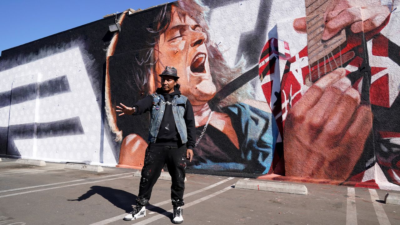 Artist Robert Vargas poses at the unveiling of his mural honoring the late guitarist Eddie Van Halen titled "Long Live The King," at Guitar Center Hollywood on what would have been the musician's 66th birthday, Tuesday, Jan. 26, 2021, in Los Angeles. (AP Photo/Chris Pizzello)