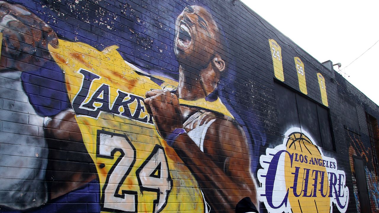 A fan pays respects at a mural depicting Kobe Bryant in a downtown Los Angeles alley on Jan. 26, 2020. (AP Photo/Matt Hartman)