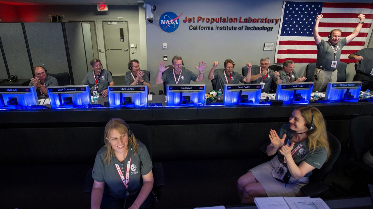 In this photo provided by NASA, Juno team members celebrate in mission control of the Space Flight Operations Facility at the Jet Propulsion Laboratory after they received confirmation from the spacecraft that it has successfully entered orbit of Jupiter, Monday, July 4, 2016, in Pasadena, Calif. (Aubrey Gemignani/NASA via AP)