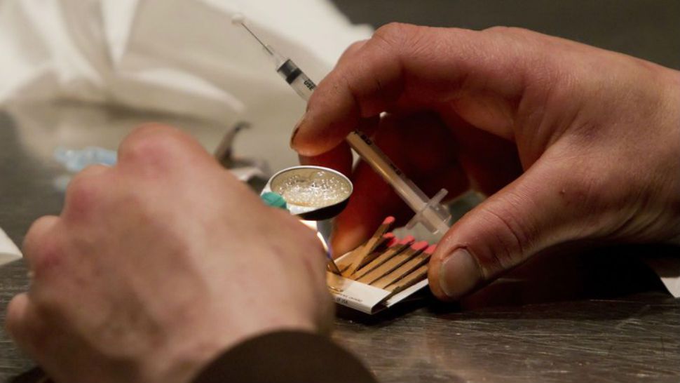 FILE - In this May 11, 2011, file photo, a man prepares heroin he bought on the street to be injected at the Insite safe injection clinic in Vancouver, British Columbia. As part of Philadelphia’s effort to combat skyrocketing opioid overdoses, city officials announced Tuesday, Jan. 23, 2018, they want to establish safe havens where people can inject drugs, after members of the city’s opioid task force visited Seattle and Vancouver in 2017. (Darryl Dyck/The Canadian Press via AP, File)