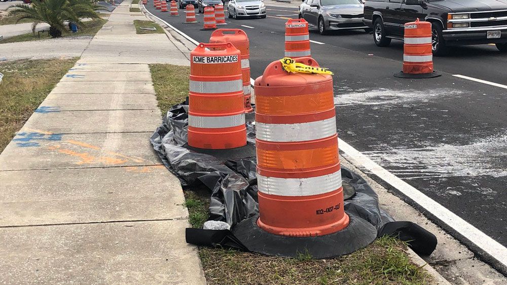 Underneath this tarp along Saxon Boulevard is a depression that could be a sinkhole, according to FDOT. (Nicole Griffin, Spectrum News)