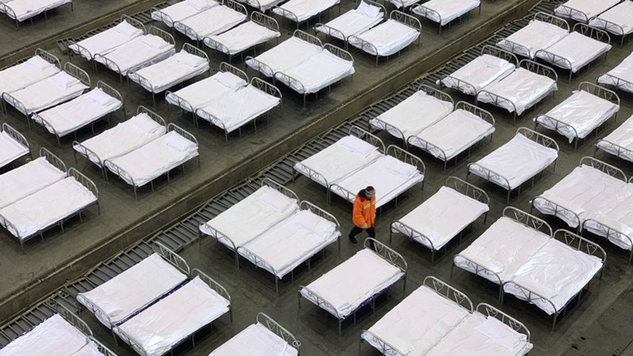 Workers arrange beds in a convention center that has been converted into a temporary hospital in Wuhan in central China's Hubei Province, Tuesday, Feb. 4, 2020. China said Tuesday the number of infections from a new virus surpassed 20,000 as medical workers and patients arrived at a new hospital and President Xi Jinping said "we have launched a people's war of prevention of the epidemic." (Chinatopix via AP)