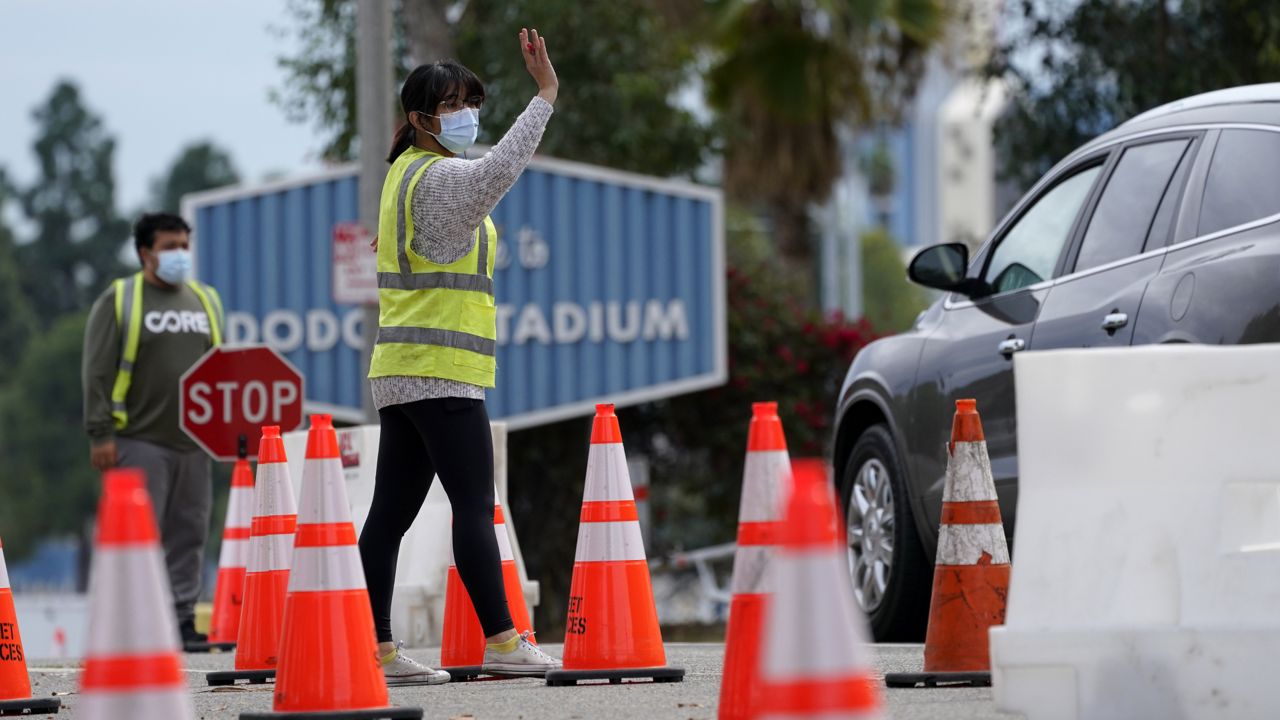 Cars are waved in as people arrive at the Dodger Stadium parking lot to receive the COVID-19 vaccine Monday, Feb. 1, 2021, in Los Angeles. (AP Photo/Mark J. Terrill)