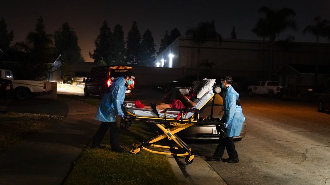 Emergency medical technicians Joshua Hammond, left, and Thomas Hoang, of Emergency Ambulance Service, transport a COVID-19 patient to an ambulance in Placentia, Calif., Friday, Jan. 8, 2021. (AP Photo/Jae C. Hong)