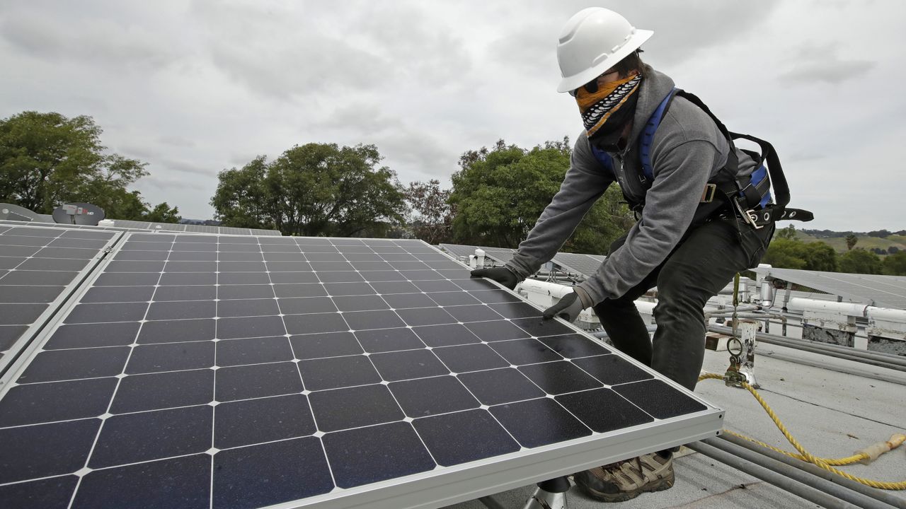 A worker installs solar panels in Hayward, Calif., on Wednesday, April 29, 2020. (AP Photo/Ben Margot)