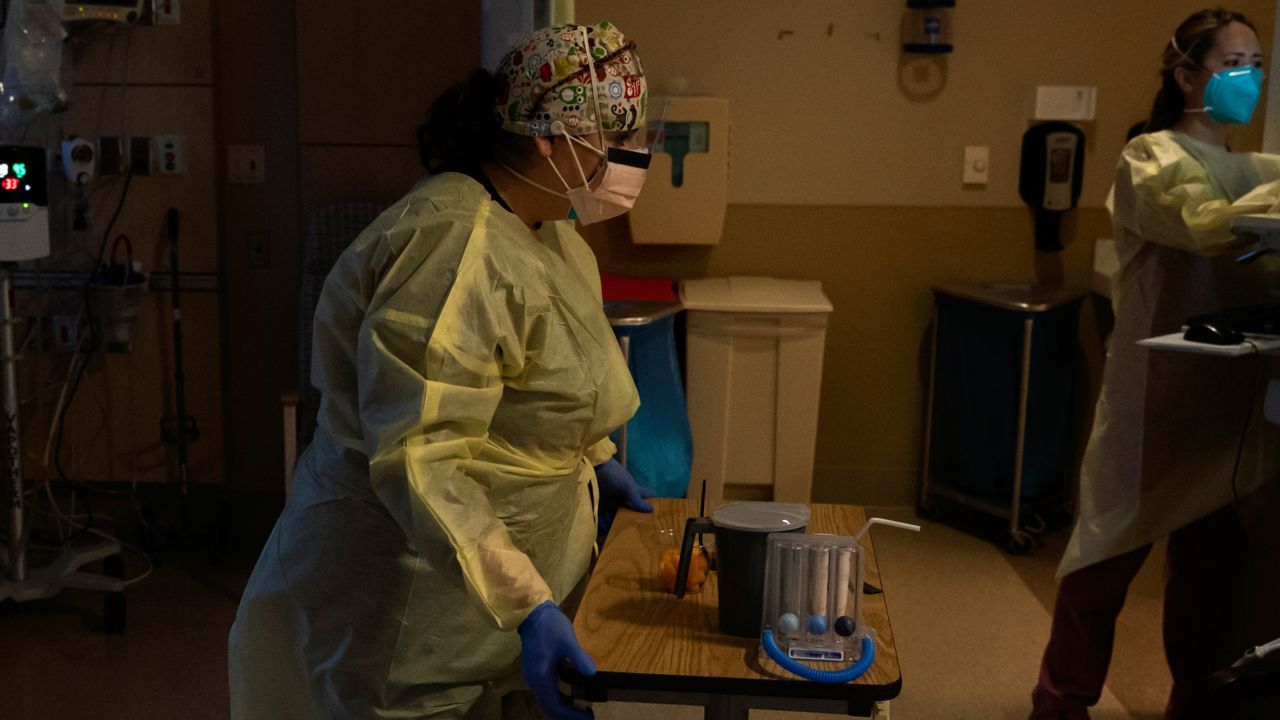 Registered nurse Nvard Termendzhyan sets up a table for a COVID-19 patient right at Providence Holy Cross Medical Center in Los Angeles, Dec. 13, 2021. (AP Photo/Jae C. Hong, File)