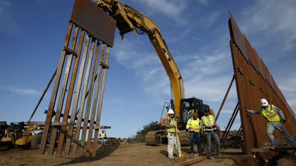 FILE - In this Jan. 9, 2019 file photo, construction crews install new border wall sections seen from Tijuana, Mexico. What started as an online fundraiser to provide President Donald Trump with donations for his southern border wall has morphed into a new foundation whose members vow to build a wall themselves. The "We The People Will Build the Wall" campaign has surpassed $20 million since it was created in December by Air Force veteran and triple amputee Brian Kolfage. (AP Photo/Gregory Bull, File)