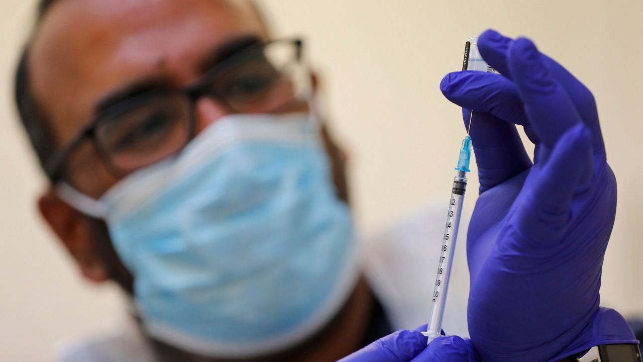 Doctor PJ Suresh draws from a vial of the Pfizer/BioNtech COVID-19 vaccine at the Fullwell Cross Medical Centre in Ilford, London, Friday, Jan. 29, 2021. Local leaders are racing to reach out to ethnic minority communities, where people are often less likely to come forward to be inoculated. 