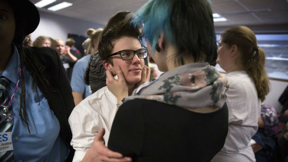 FILE - In this Dec. 4, 2014 file photo, Elliott Kunerth, 17, a transgender male high school student in Mankato, hugs his girlfriend, Kelsi Pettit, 17, after the Minnesota State High School League board voted to pass the Model Gender Identity Participation in MSHSL Activities Policy in Brooklyn Park, Minn. A study released Monday, Feb. 5, 2018, from an analysis of a 2016 statewide survey of nearly 81,000 Minnesota teens, suggests that far more U.S. teens are transgender or gender nonconforming than previously thought, with many rejecting the idea that girl and boy are the only possible genders. (Leila Navidi/Star Tribune via AP)