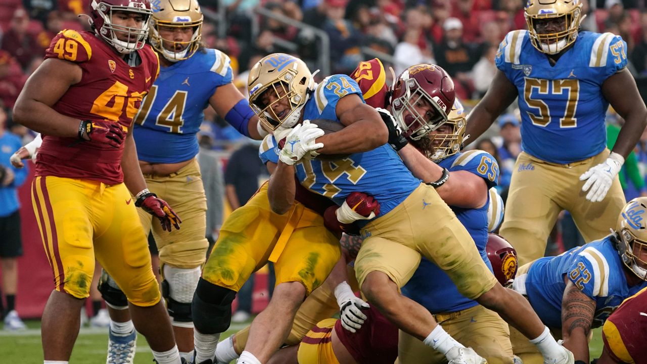 UCLA running back Zach Charbonnet (24) runs the ball in for a touch down as Southern California defensive lineman Jacob Lichtenstein (97) tries to stop him during the second half of an NCAA college football game Saturday, Nov. 20, 2021, in Los Angeles. (AP Photo/Mark J. Terrill, File)