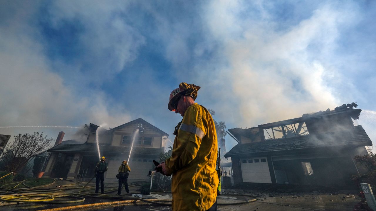 Firefighters extinguish burning homes Thursday, Feb. 10, 2022, in Whittier, Calif. At least two homes were destroyed in a brush fire that blackened about four acres in Whittier area Friday. (AP Photo/Ringo H.W. Chiu)