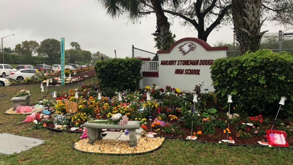 Days after the shooting in February 2018, remembrances of those who were killed were placed outside the sign at Marjory Stoneman Douglas High School in Parkland, Fla. (Spectrum News)