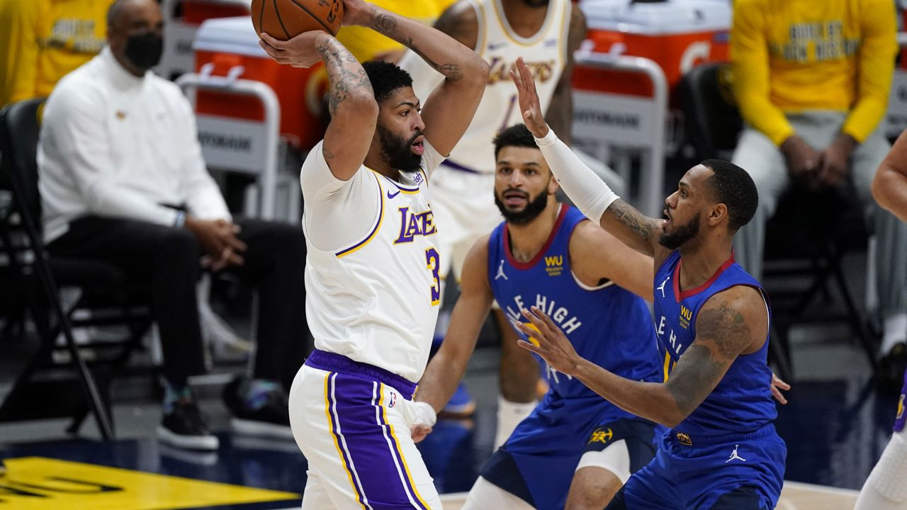 Los Angeles Lakers forward Anthony Davis, left, looks to pass the ball as Denver Nuggets guards Jamal Murray, center, and Monte Morris defend during the first half of an NBA basketball game Sunday, Feb. 14, 2021, in Denver. (AP Photo/David Zalubowski)