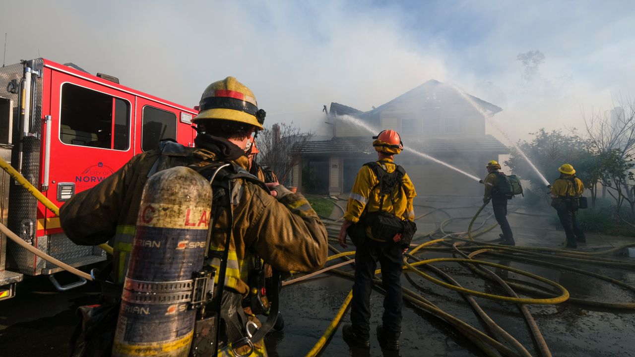 Firefighters extinguish a burning house Thursday, Feb. 10, 2022, in Whittier, Calif. At least two homes were destroyed in a brush fire that blackened about four acres in the Whittier area Thursday. (AP Photo/Ringo H.W. Chiu)