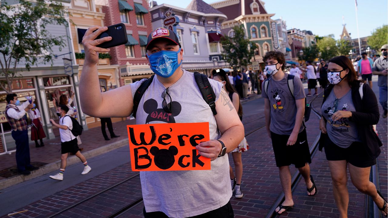 Guests walk down Main Street USA at Disneyland in Anaheim, Calif., Friday, April 30, 2021. (AP Photo/Jae Hong)