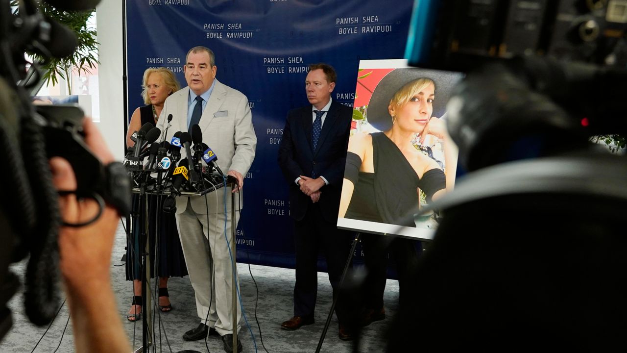 Randi McGinn, from left, Brian Panish and Kevin Boyle, attorneys for the family of cinematographer Halyna Hutchins, stand next to a portrait of Hutchins during a news conference, Tuesday, Feb. 15, 2022, in Los Angeles. (AP Photo/Chris Pizzello)