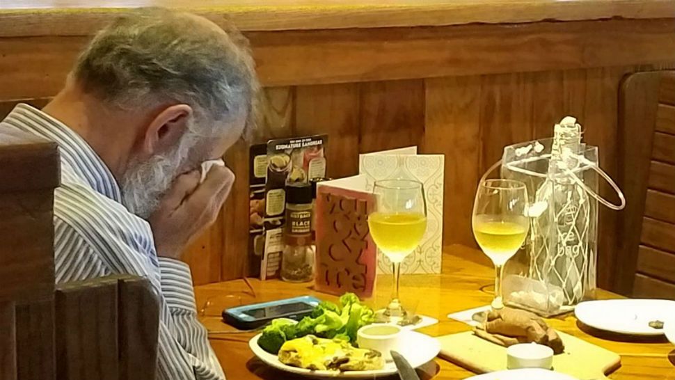 Man weeps into napkin across from wife's ashes. Image/Chasidy Gwaltney