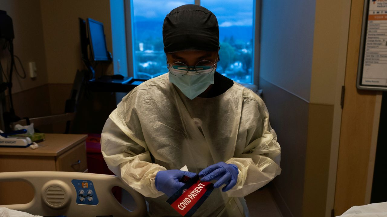 Registered nurse Bryan Hofilena attaches a "COVID Patient" sticker on a body bag of a patient who died of coronavirus at Providence Holy Cross Medical Center in Los Angeles, on Dec. 14, 2021. (AP Photo/Jae C. Hong, File )