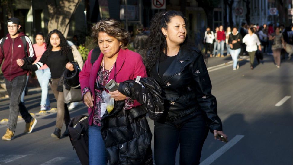 People walk down the center of a street in the Roma neighborhood after an earthquake shook Mexico City, Friday, Feb. 16, 2018. (AP Photo/Rebecca Blackwell)