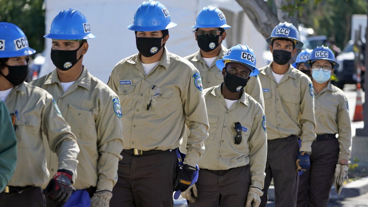 Members of the California Conservation Corps line up to help with the setup of a new federal COVID-19 vaccination center on the campus of the California State University Los Angeles Friday, Feb. 12, 2021, in Los Angeles. (AP Photo/Marcio Jose Sanchez)