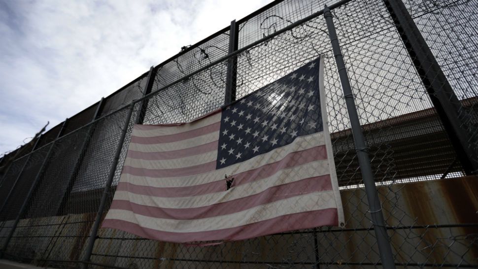 In this Monday, Jan. 21, 2019, photo, a U.S. flag hangs on a border barrier in El Paso, Texas. Such barriers have been a part of El Paso for decades and are currently being expanded, even as the fight over President Donald Trump's desire to wall off the entire U.S.-Mexico border has sparked the longest government shutdown in the nation's history.(AP Photo/Eric Gay)