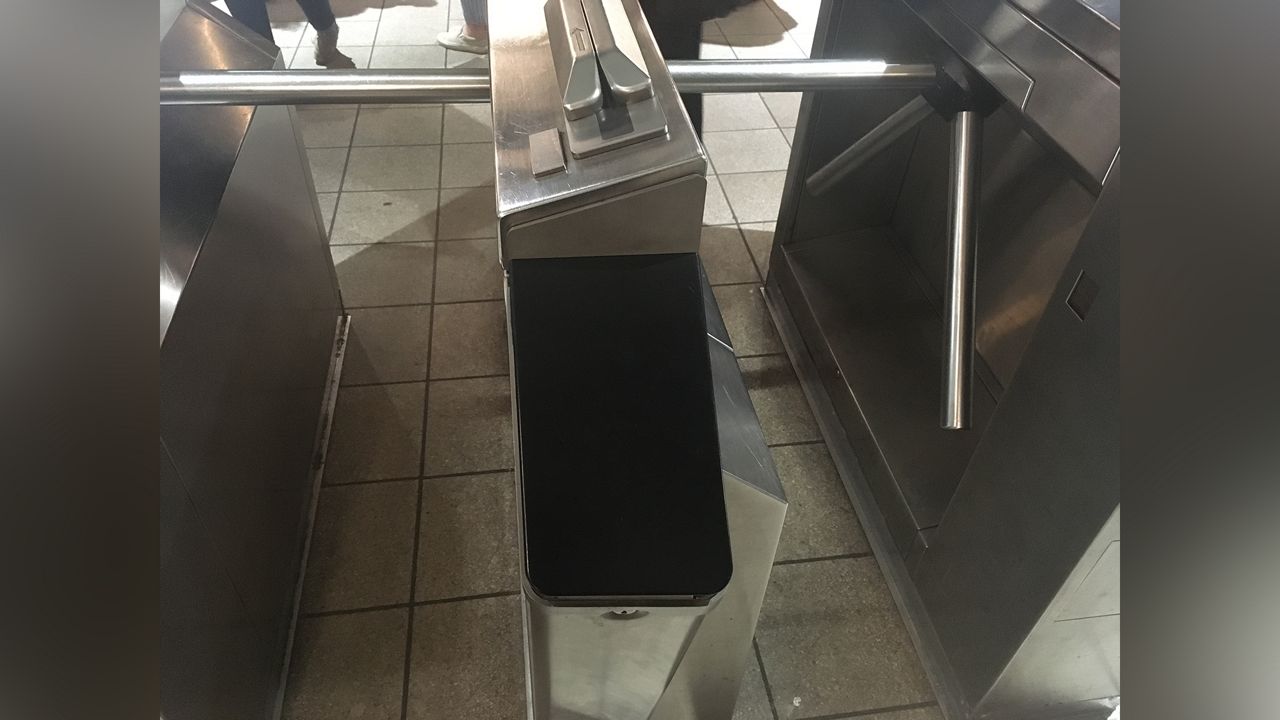 A black device attached to a silver subway turnstile.