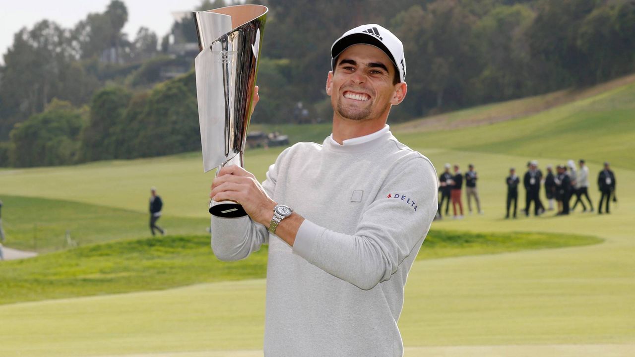 Joaquin Niemann, of Chile, reacts with his trophy on the 18th green after winning the Genesis Invitational golf tournament at Riviera Country Club, Sunday, Feb. 20, 2022, in the Pacific Palisades area of Los Angeles. (AP Photo/Ryan Kang)