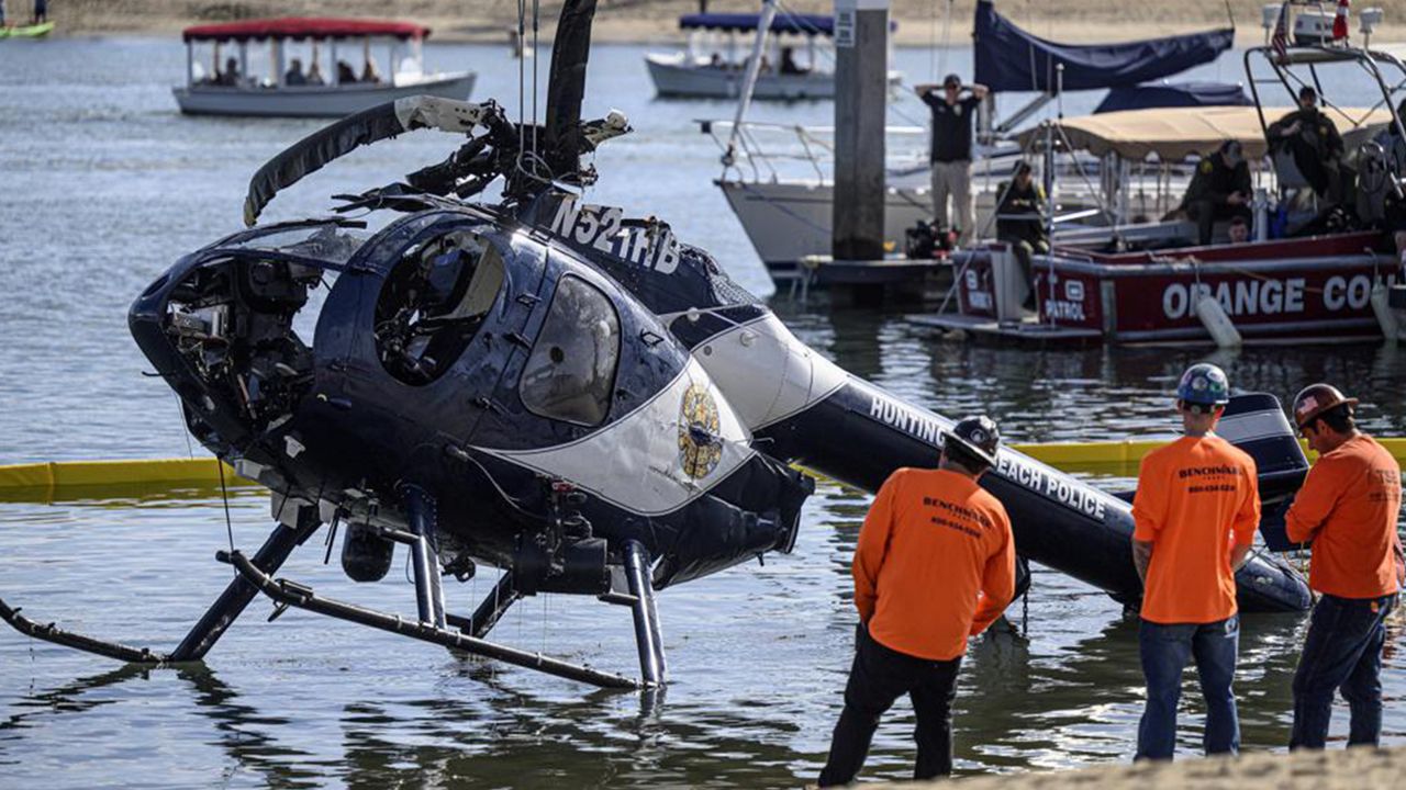 A crane is used to lift a Huntington Beach Police helicopter out of the water in Newport Beach, Calif., Sunday, Feb. 20, 2022. (Mindy Schauer/The Orange County Register via AP)