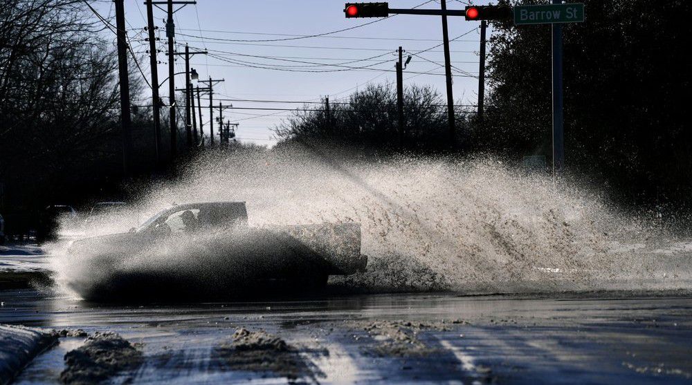 A pickup sends a wake of snow melt high into the air as the driver plows through a large puddle at Barrow and South 11th streets intersection in Abilene, Texas, Friday, Feb. 19, 2021. (Ronald W. Erdrich, The Abilene Reporter-News via AP)