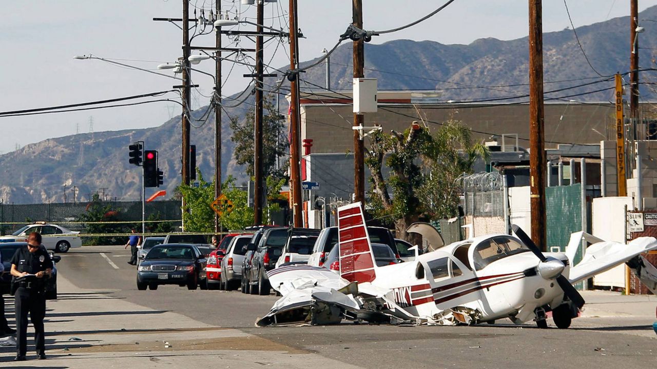 The wreckage of a small plane that crashed on approach to Whiteman Airport, background, is seen in the Pacoima area of Los Angeles' San Fernando Valley, Feb. 22, 2016. (AP Photo/Nick Ut)