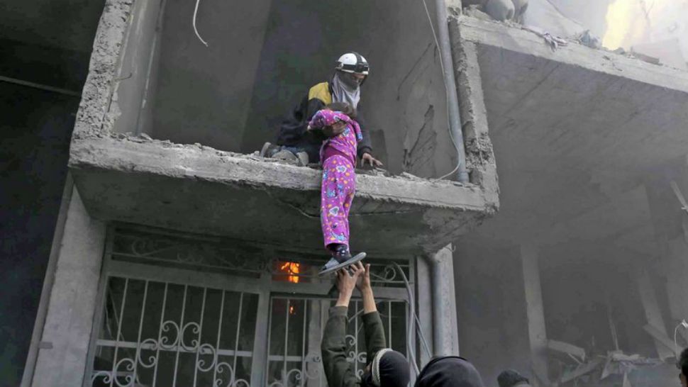 In this photo released on Wednesday Feb. 21, 2018 provided by the Syrian Civil Defense group known as the White Helmets, shows a member of the Syrian Civil Defense group rescuing a young girl from a damaged damaged by airstrikes and shelling by Syrian government forces, in Ghouta, a suburb of Damascus, Syria. New airstrikes and shelling on the besieged, rebel-held suburbs of the Syrian capital killed at least 10 people on Wednesday, a rescue organization and a monitoring group said. (Syrian Civil Defense White Helmets via AP)