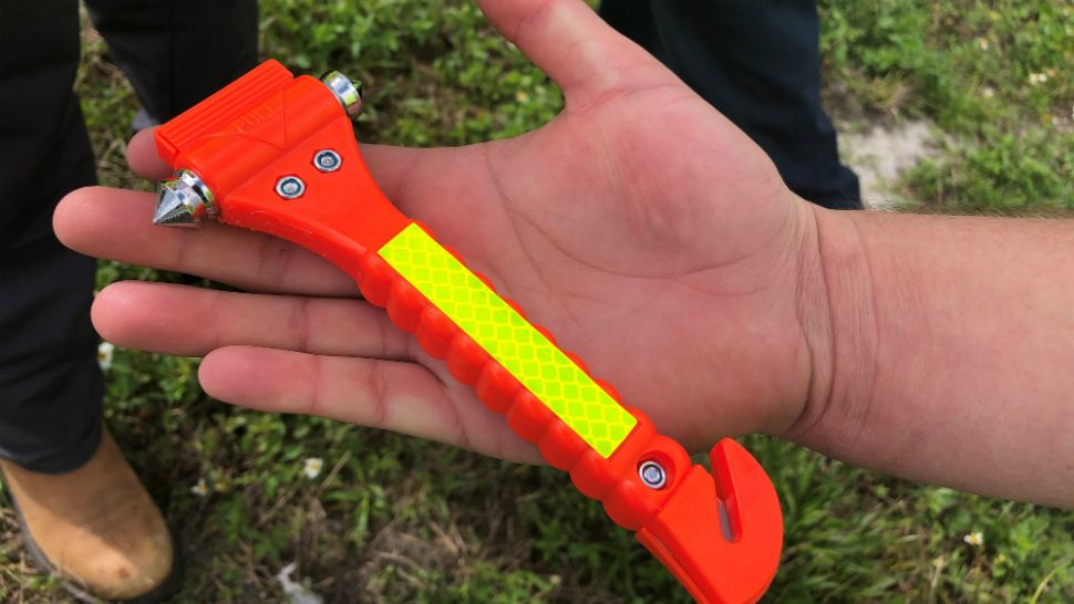 Garrett Popovich shows off the fluorescent-colored tool he used to break the glass of a vehicle sinking in a retention pond. (Tony Rojek/Spectrum News)